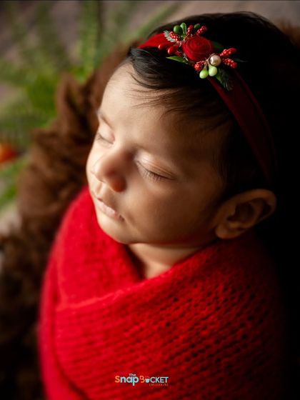 A detailed close-up of the baby's face and the delicate red floral headband. I pay close attention to these small accessories that complete the look.