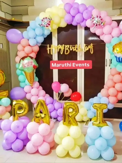 A sweet pastel-colored circular balloon arch for a second birthday. The individual letter balloons spelling out the name "PARI" add a lovely personal touch.