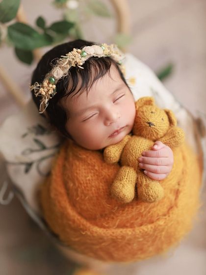 Sunshine and snuggles. This little one is cuddling a tiny teddy bear, wrapped in a beautiful mustard color that just radiates warmth.