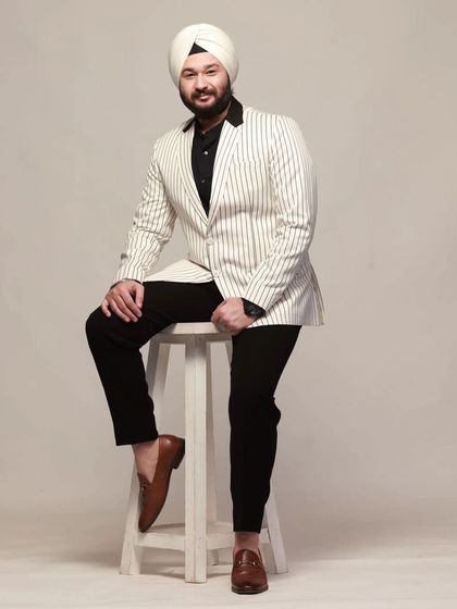 Sustainable fashion is the future. A model looking stylish in our white pinstripe blazer with a black shawl collar, paired with black trousers.