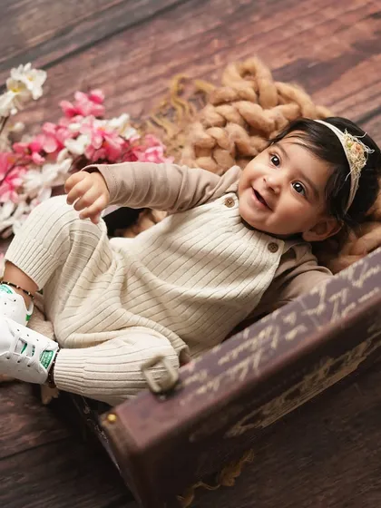 A joyful, reclining pose from the baby girl in her suitcase. Her happy expression and cute sneakers make this a fun and modern baby portrait.