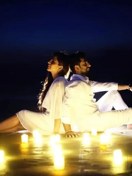 A simple yet powerful pre-wedding concept. The couple sits back-to-back, surrounded by candles, creating an intimate and serene image that focuses purely on their connection.