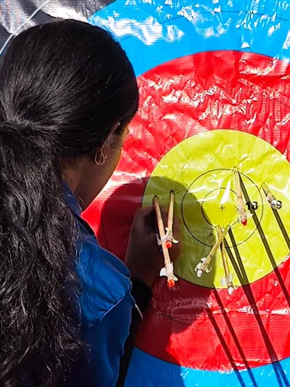 A female archer scoring her arrows. Precision and attention to detail are skills we nurture in all our students.