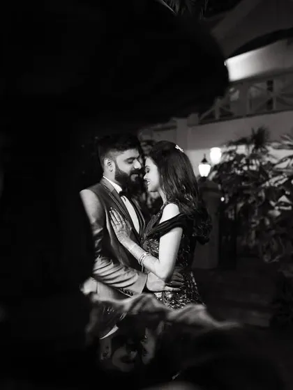 A romantic black and white photo of a couple at night, framed by a fountain. The low light and classic feel make this an incredibly intimate and moody portrait.