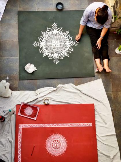 An artist creating a large-scale Aipan rangoli on the floor, a traditional art form from the Kumaon region of India.