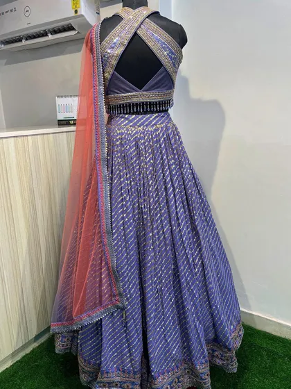 I love the back of this purple lehenga with its stylish criss-cross design. The halter neck blouse is heavily embellished, contrasting beautifully with the striped skirt.