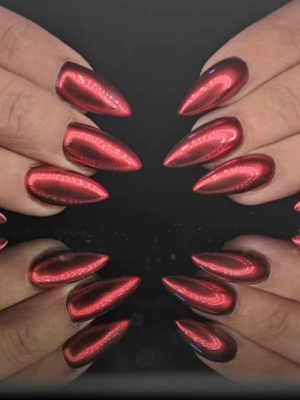 A full view of the red chrome stiletto nails, reflecting light for an intensely vibrant and glossy finish.