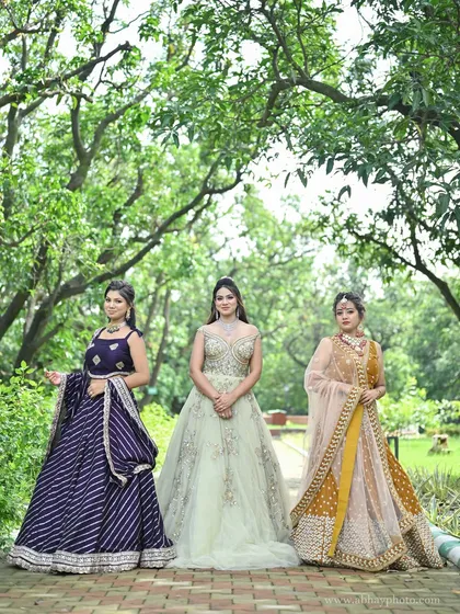 Our festive collection on display. This photo features three models wearing a purple leheriya lehenga, a pastel green gown, and a mustard yellow lehenga, showing different styles for various events.