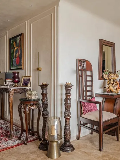 The corner of the 'Eternity' living room, showing the blend of traditional Indian furniture and modern art. The intricate woodwork and classic decor pieces add a layer of history and elegance.