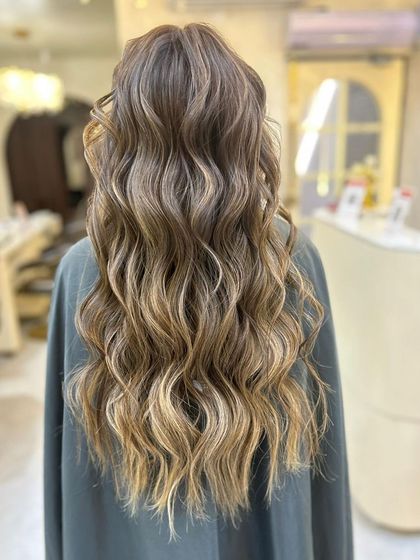 A full view of the stunning olive ashy brown balayage. The long, wavy hair looks incredibly healthy and stylish.