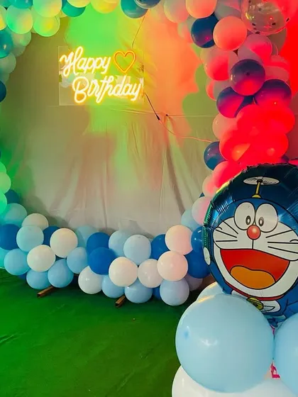 A close-up of the Doraemon balloon sculpture and the neon 'Happy Birthday' sign, highlighting the details of the decor.