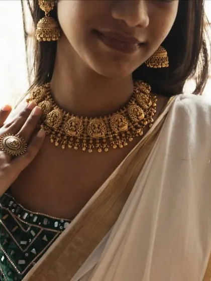 A close-up shot of a model wearing our temple choker with a traditional South Indian saree. The intricate carvings of deities on the choker are a highlight of this design.