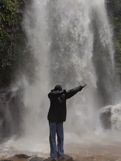 A trekker dabbing in front of Hidlumane Falls, capturing the fun and energetic vibe of our group.