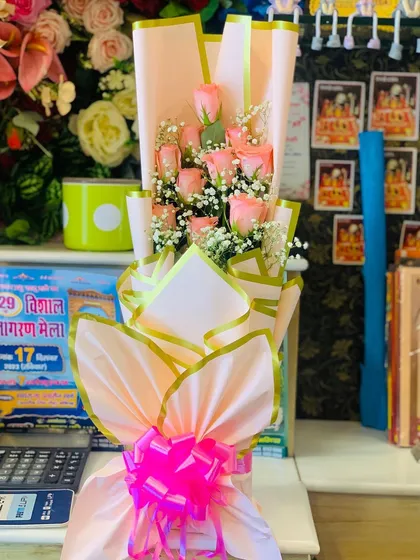 A tall and elegant bouquet of pink roses and baby's breath. The layered pink wrapping with gold trim gives the arrangement height and a luxurious feel.