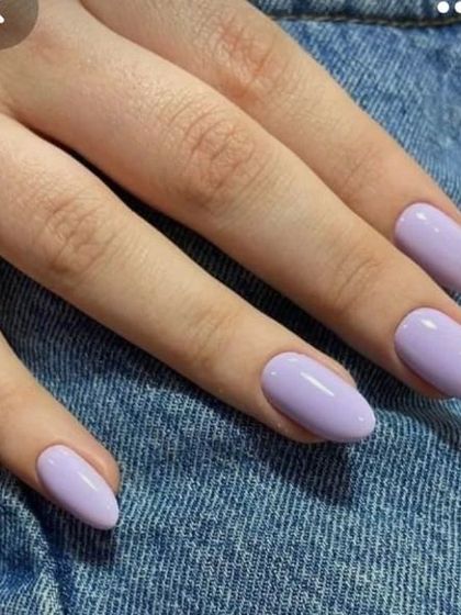 A beautiful solid color manicure in a trendy pastel lavender shade on medium-length almond nails.