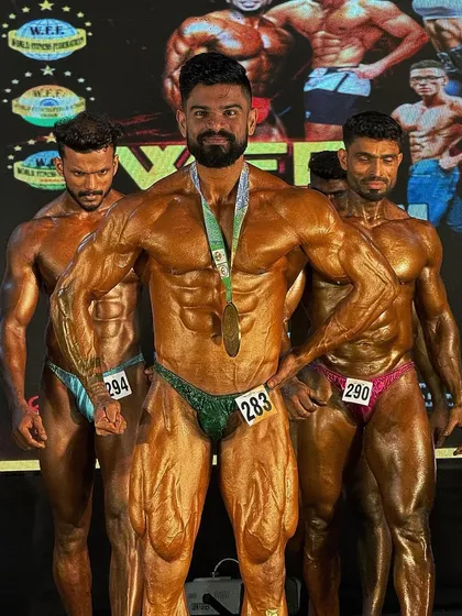 A champion on stage. This image captures the final result of months of disciplined contest prep, from diet and training to posing. Earning a medal is the validation of a correctly executed plan.