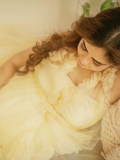 An intimate, high-angle shot focusing on the mother-to-be's peaceful expression. This perspective offers a different, more personal view of her quiet moment in the sunlit boho studio.