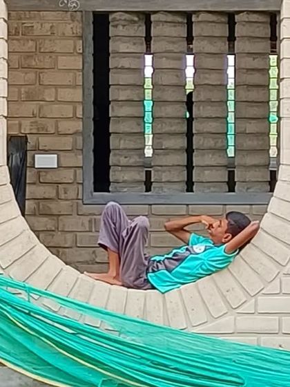 A child relaxing in one of the inverted circular openings at Sai Kirupa Special School. These playful niches have become favorite spots for the children, demonstrating how architecture can create moments of comfort and delight.