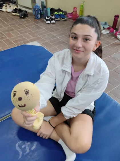 A happy student holds up her finished puppet. The smile on her face is the best reward for me as a teacher.