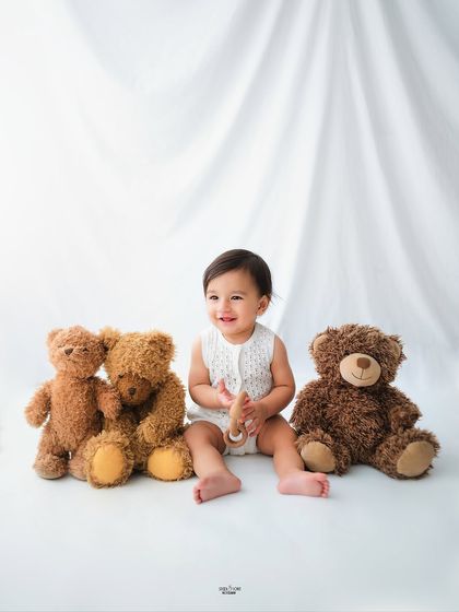 A classic portrait of a happy baby surrounded by his favorite teddy bear friends.