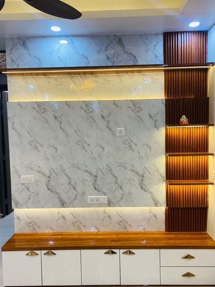 A beautiful TV unit with a white marble back panel, a wooden console, and lit-up vertical shelves with a fluted background.