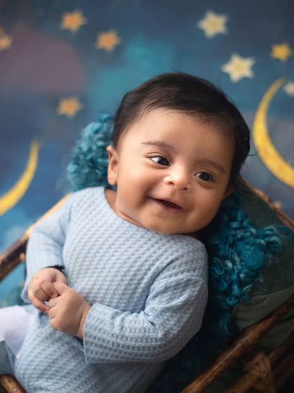 Bright eyes and chubby cheeks. This little one's sweet smile against the starry night backdrop is a winning combination for a simple and beautiful baby portrait.