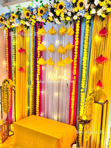A side view of the vibrant Mehendi decor, highlighting the layers of colorful drapes and the hanging marigold garlands.