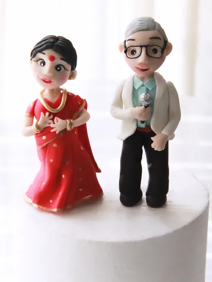 A close-up of the custom toppers for the 25th anniversary cake, showing the husband with his microphone and the wife in a dancing pose, all handcrafted from fondant.
