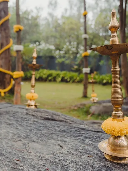 Creating a serene ambiance for an outdoor wedding ceremony. I placed traditional brass lamps on natural rock formations, decorated with marigold flowers to complement the rustic, natural setting.