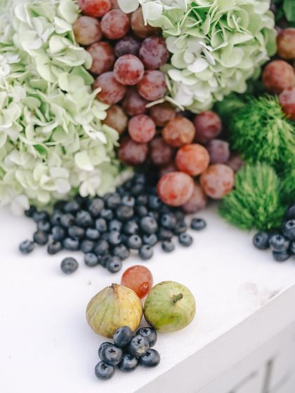 A quiet celebration of abundance. This tablescape for a sit-down dinner features soft ivories and nature's own palette, with blueberries, figs, and Australian grapes nestled among fresh greens.