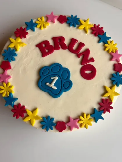 A vibrant and colorful round cake for Bruno's first birthday. We use natural food colorings to create these fun floral and star patterns.
