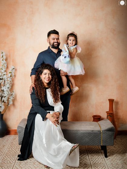 A beautiful family portrait, with mom, dad, and their little girl posing together in a relaxed and happy moment.
