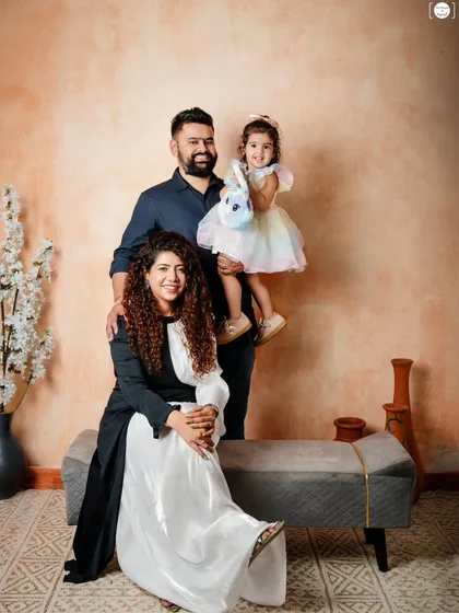 A beautiful family portrait, with mom, dad, and their little girl posing together in a relaxed and happy moment.