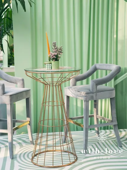 A high-top table and bar stools in 'The Conservatory', providing a chic and comfortable spot for guests to enjoy a drink.