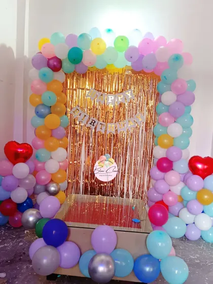 A multi-colored pastel balloon arch with a gold shimmer curtain, ideal for a vibrant birthday party.