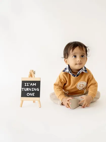 A simple and clean first birthday portrait with a small chalkboard sign announcing "I'm turning one."