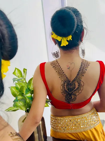 The client admiring her back henna in the mirror. This type of design is a bold and beautiful choice for a special occasion.
