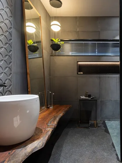 A focused view on the bathroom vanity, showcasing the organic shape of the wood and the modern vessel sink. Pendant lighting adds a soft glow to the moody, sophisticated space.