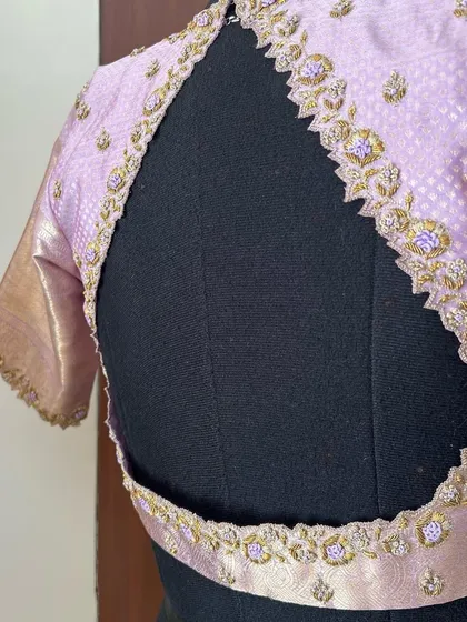 The back of our pastel lilac blouse, showcasing a unique cutout design framed with delicate, scalloped zardosi embroidery.