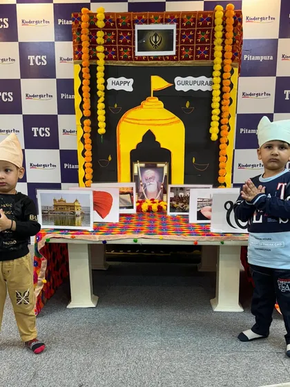 Two children stand with folded hands in front of our Gurpurab display, a setup designed to introduce them to the symbols and teachings of Sikhism.