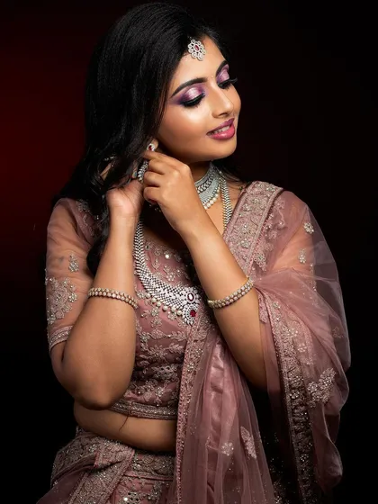 This North Indian bridal look features a soft, dusty rose lehenga paired with diamond jewelry. The makeup focuses on a subtle smokey eye and a matching lip color for a modern yet traditional feel.