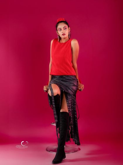 A confident and poised stance on the stool. The composition is clean and allows the red and black outfit to make a statement.