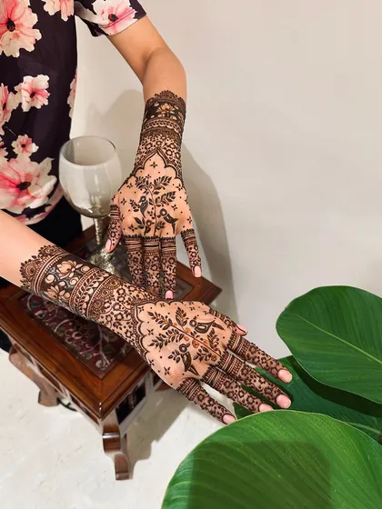 The back of the hands feature a delicate and intricate floral pattern, offering a softer contrast to the bold motifs on the palms.