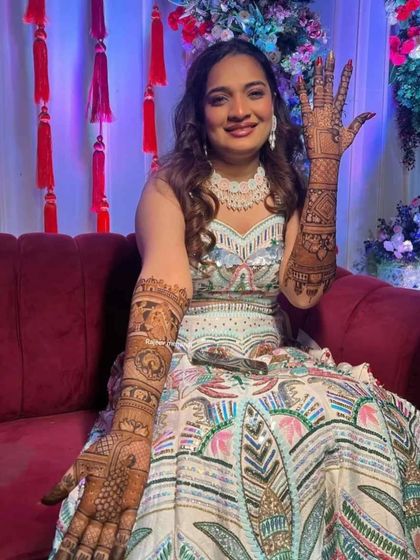 A beautiful bride in her ceremony lehenga, showing her full arm mehendi.