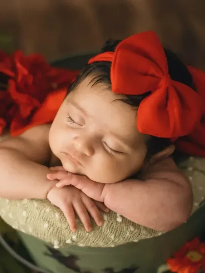 A sweet portrait of the baby girl with a little pout, sleeping soundly in her red-themed setup.