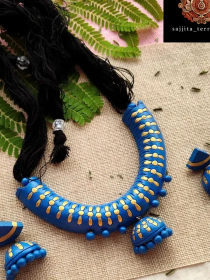 This is my 'hansli' or collar-style necklace, designed to sit elegantly on the neckline for a bold, modern statement. The deep blue is accented with delicate gold patterns, and the set includes a hanging jhumka and matching half-moon earrings.