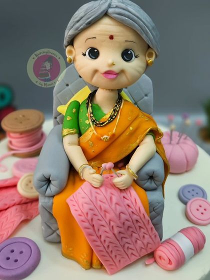 A detailed figurine of a grandmother in a beautiful saree, knitting peacefully in her chair. This was for a 75th birthday celebration.