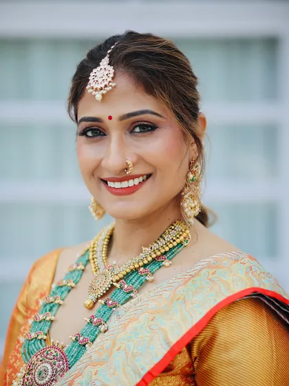 A close-up that radiates happiness. The bride's makeup features a beautiful bronze eye and a warm, terracotta lip color that complements her traditional jewellery.