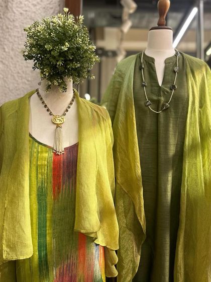 Soft drapes and rich colors. This display features layered tunics in shades of green, from olive to chartreuse, paired with statement necklaces.
