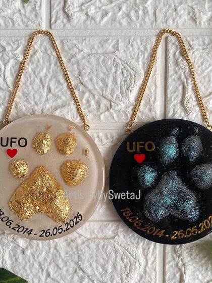 A full view of both the gold and cosmic pawprint plaques hanging by their chains. They are designed to be displayed in a special place, keeping the memory of a furry friend alive.